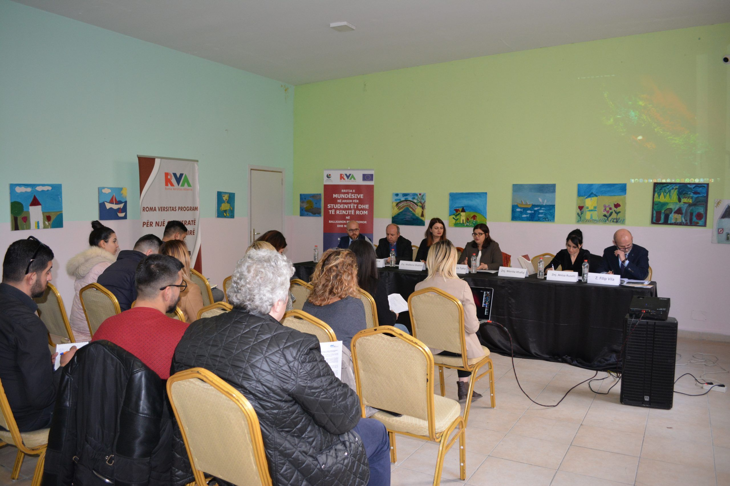 An audience seated before a panel at a public roundtable on Roma education