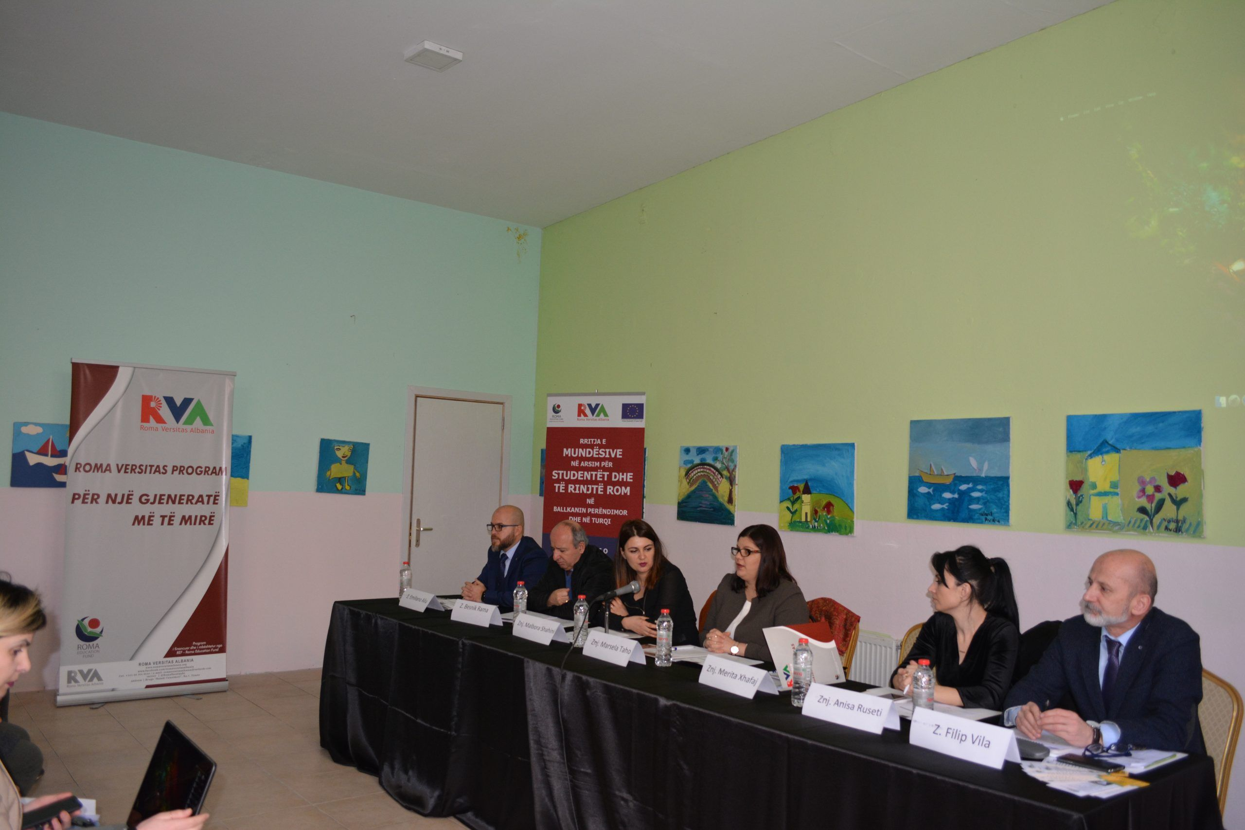 Speakers at a Roma Versitas Albania roundtable, beside the programme banner
