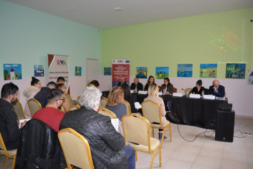 An audience seated before a panel at a public roundtable on Roma education
